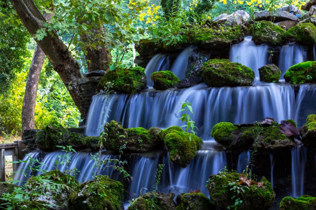 A serene waterfall cascading over mossy rocks surrounded by dense greenery in Beyköy, Düzce, Türkiye.